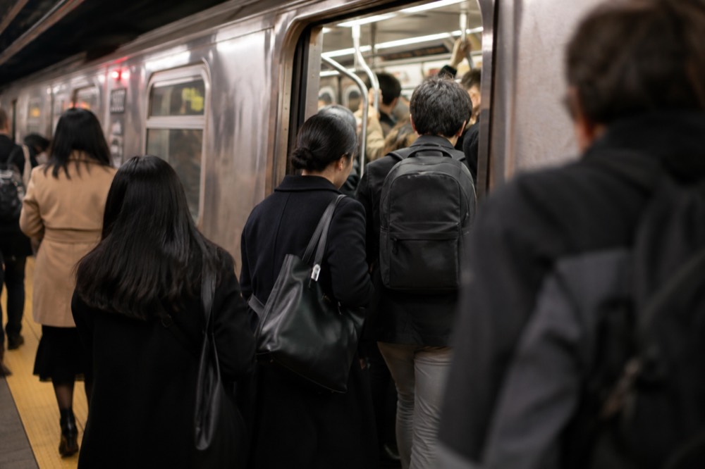 Riders stepping onto a crowded subway train during the evening rush