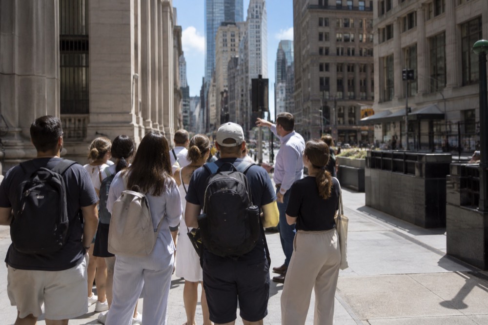 A walking tour group listening to a guide on a Lower Manhattan street