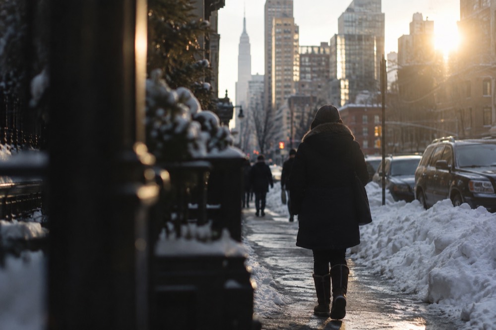 Snow-covered New York street with a person in a heavy coat and waterproof boots