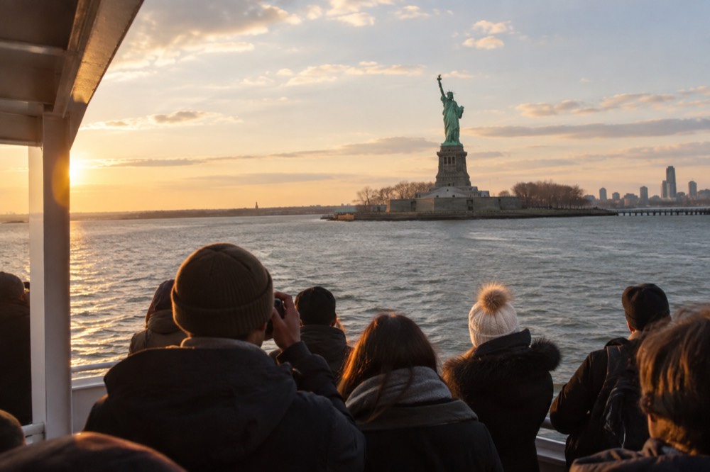 The Statue of Liberty seen from a ferry deck approaching Liberty Island in early light
