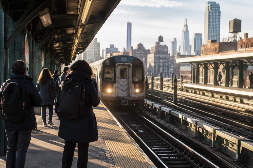 A subway platform in Manhattan with a train arriving and passengers waiting