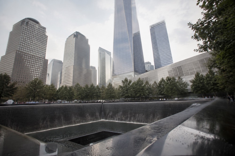 The reflecting pools of the 9/11 Memorial with One World Trade Center rising behind them