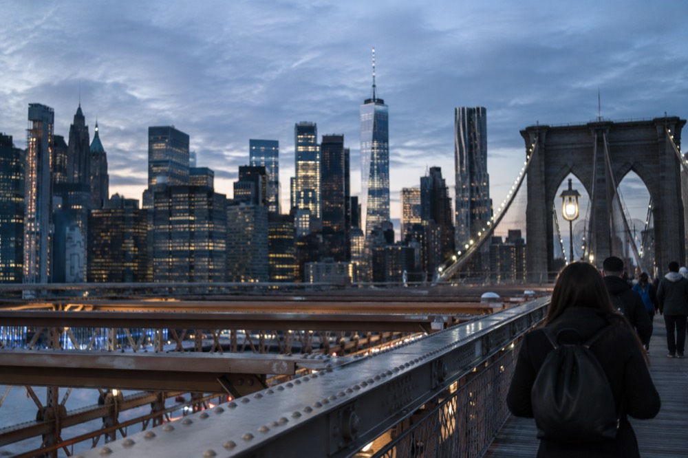 The Brooklyn Bridge promenade with the Manhattan skyline rising behind the suspension cables